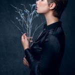 Side profile of athletic model holding delicate winter branches, photographed by Misha Svetlov in dark contemplative style